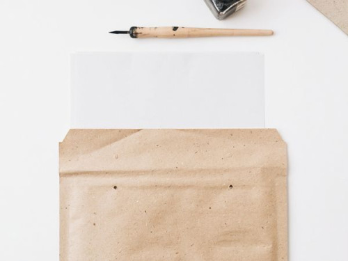 Pochette d'envoi bulle en papier d'herbe posée sur un fond blanc
