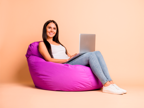 Une femme assise avec son ordinateur dans un pouf géant