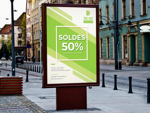 Affiche verte SOLDES posée sur un panneau d'affichage extérieur